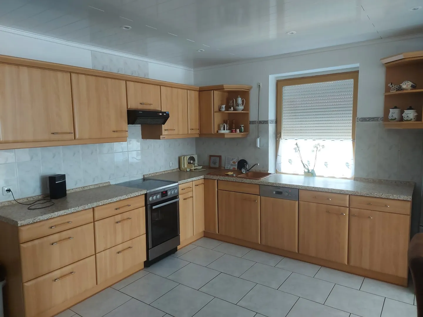 Küche der Ferienwohnung mit Holzfronten, Backofen, Kochfeld und Fenster